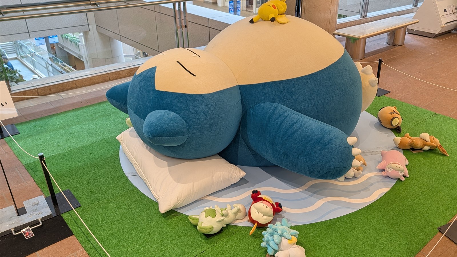 枕とぬいぐるみに囲まれて眠る、中くらいのサイズのカビゴン